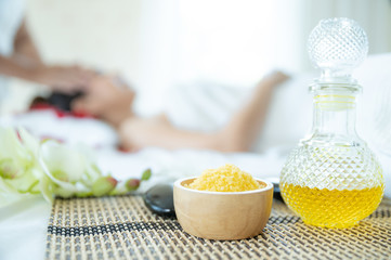 Bottle of oil and spa salt With the background as Beautiful woman taking a spa facial. Beautiful female taking facial massage treatment in the spa salon.