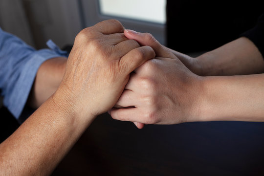 young woman is holding old woman's hand