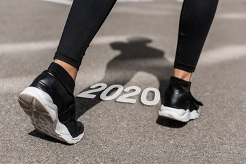 cropped view of sportswoman on running track near 2020 lettering
