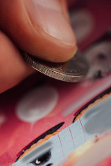 close up view of silver coin in hand of gambler scratching lottery ticket