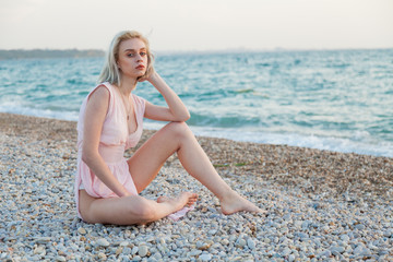 Fototapeta na wymiar Beautiful fashionable blonde woman on the beach by the ocean