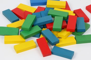 heap of colorful wooden building blocks are lying in a white studio