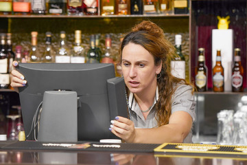 Portrait of woman bartender hotel bar made a mistake in the bill. A barmaid registrating new order by cash register. A restaurant worker registrating new order. The concept of service.  