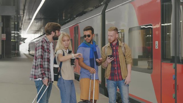 Group of tourists checking time and waiting for delayed train on platform