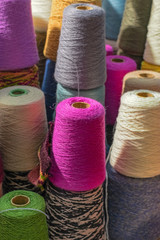 A bobbins of multi-colored natural yarn in the sun. Soft focus.