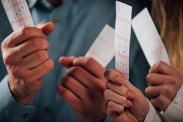 cropped view of man and woman holding lottery tickets while waiting for lottery results