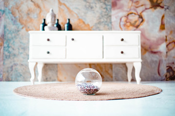 A white dresser near an abstract wall. Mirror disco ball on the carpet in the apartment