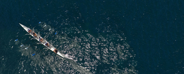 Aerial drone ultra wide photo of team of fit women practising in sport canoe in deep blue open...