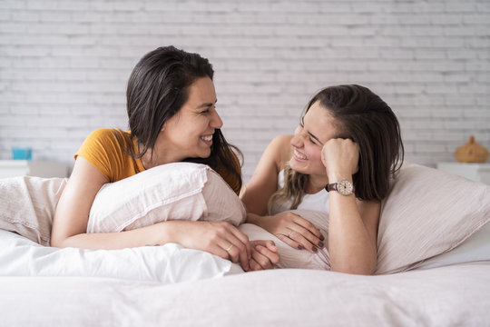 Happy lesbian couple lying in bed