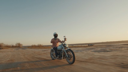 Motorcyclist driving his motorcycle on the dirt road during sunset