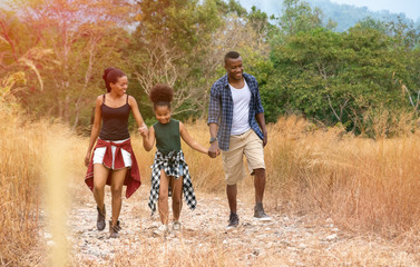 Fototapeta premium Happy mixed race family father, mother and child daughter walking on country road. Travel vacation concept