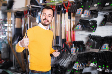 Man choosing various tools in garden equipment shop