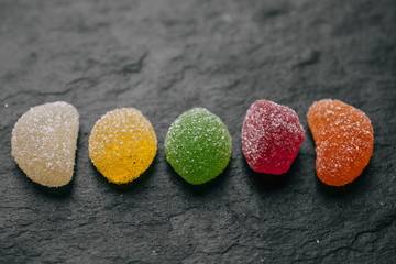 Different fruity jelly candies on black slate background. 