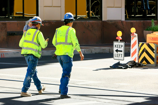 Two construction workers wearing their hard-hats and high viz vests walk back to their jobs on a downtown project in Tucson AZ