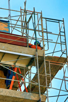 Two construction workers wearing safety equipment as they go about their jobs high up on scaffolding at an apartment building project in Tucson AZ