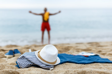 Glad male resting. Clothes on the sand near sea