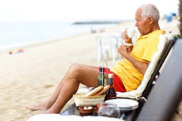 Nice mature man sitting with cup of hot drink