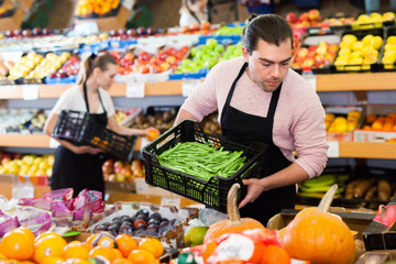Obraz premium Young man with box of beans and woman wearing apron on background on the supermarket
