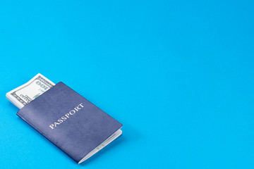 Blue passport with american dollars in 100 bills on a blue background