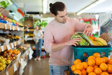 Obraz premium Man standing with full grocery cart during shopping in fruit shop