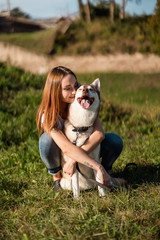 Happy young woman hugging her dog on a meadow