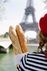 Woman standing with baguettes in Paris. Eiffel Tower in the background. French theme and vibes. 