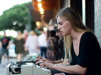 A young female types a poem on her vintage typewriter