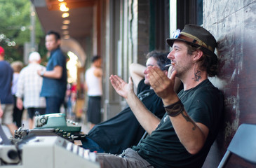 A street poet pitches sales to clients passing by on the sidewalk in downtown Austin, TX