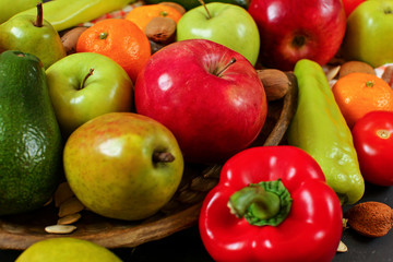 Mixed fruit - apples, pears, tangerines; and vegetable - peppers, tomatoes, avocados; with some whole almonds and nuts, closeup photo