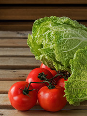 Chinese cabbage located and fresh tomatoes on a brown wooden background. close up. Selective focus on tomatoes. Vertical orientation.