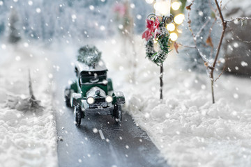 Miniature classic car carrying a christmas tree on winter