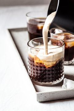 Close up of milk pouring over iced coffee