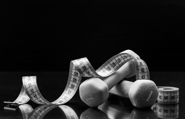  measuring tape and dumbbells on a black background