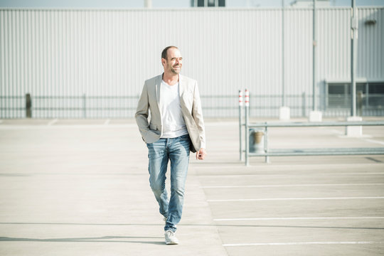 Happy mature businessman walking on parking deck