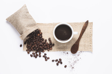 white coffee cup , coffee beans spilled out of the bag, wooden spoon with coffe on white background. Top view.