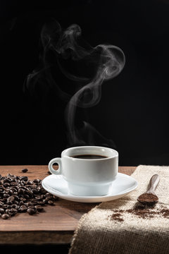 Warm coffe smoke, with .coffee beans. wooden spoon with coffe on wooden base, on dark background.