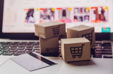 Online shopping - Paper cartons or parcel with a shopping cart logo and credit card on a laptop keyboard. Shopping service on The online web and offers home delivery..