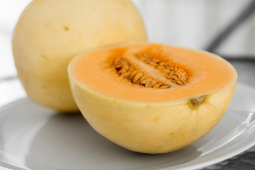 Fresh sweet orange melon on the white plate as a background with a selective focusing. Useful and vitamin-rich food. Vegeterian.