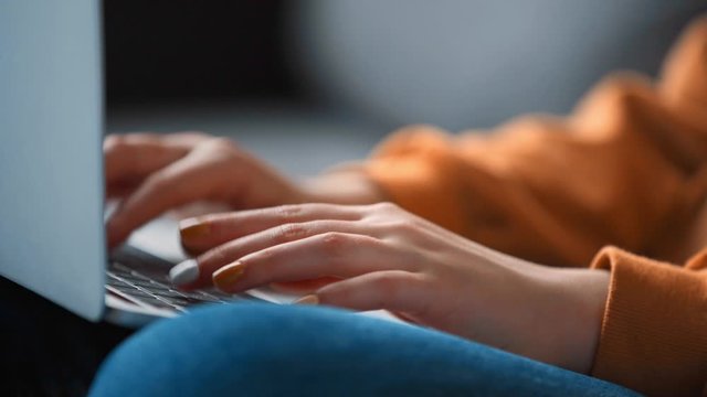 cropped view of teenage girl typing on laptop