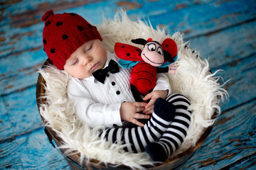 Little baby boy with knitted ladybug hat and pants in a basket