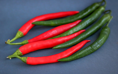 Still life of red and green hot chili peppers against a dark background.