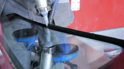 A mechanic is fixing the front window on the car.