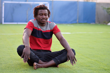 A Ghanaian African boy doing yoga in garden 