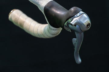 Road bike handlebars and dual control lever on a black background. Handlebar tape white. Bicycle repair in a modern workshop.