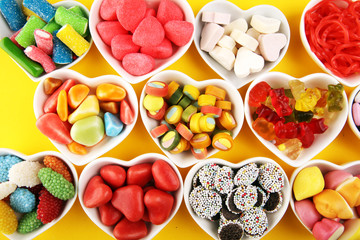 candies with jelly and sugar. colorful array of different childs sweets and treats on yellow background