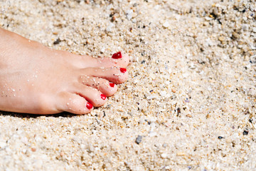 Foot of a woman in the sand on the beach