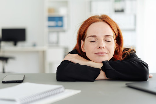 Serene young woman closing her eyes at the office