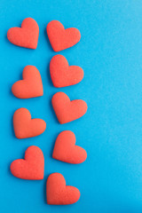 Red hearts shaped cookies on the blue background. Copy space. Top view. Location vertical.