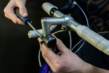 Road bike handlebars and dual control lever on a black background. Install handlebar tape white. Bicycle repair in a modern workshop. White insulating tape close-up.