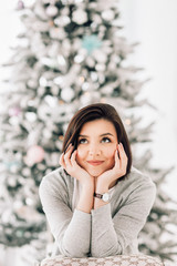 A young beautiful woman dreaming near the christmas tree. Cristmas time, waiting for a miracle